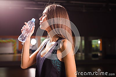 Side view of beautiful girl in sport clothes drinking water after workout in gym Stock Photo