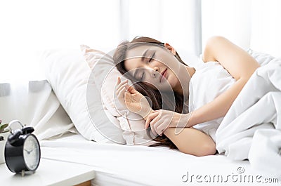 Side view of beautiful young Asian woman smiling while sleeping in her bed and relaxing in the morning. Lady enjoying sweet dreams Stock Photo