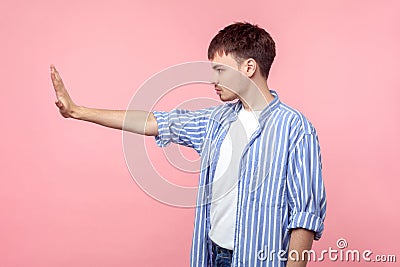 Side view portrait of bossy serious brown-haired man standing with raised palm showing stop gesture. isolated on pink background Stock Photo