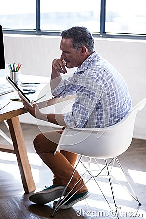 Side view of businessman reflecting and using a tablet computer Stock Photo