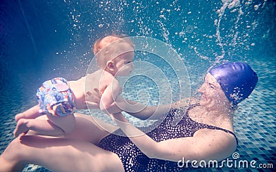 Young woman holding baby underwater in pool. Stock Photo