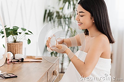 Cheerful asian woman cleaning her face with toner Stock Photo