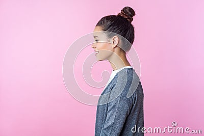 Side view of cheerful brunette teenage girl smiling, looking kind and positive, empty copy space for advertisement. pink Stock Photo