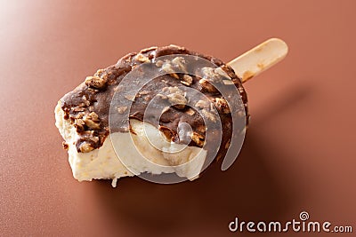 Side view chocolate outer ice cream with peanuts on a brown background with some bite Stock Photo