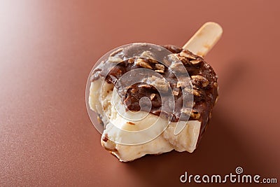 Side view chocolate outer ice cream with peanuts on a brown background with bites Stock Photo