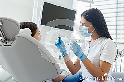 Side view of dentist in mask examining teeth of small client in the hospital Stock Photo