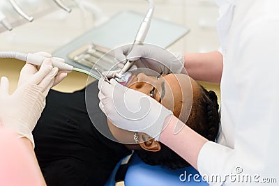 Side view of dentist and nurse making professional teeth cleaning female young patient at the dental office Stock Photo