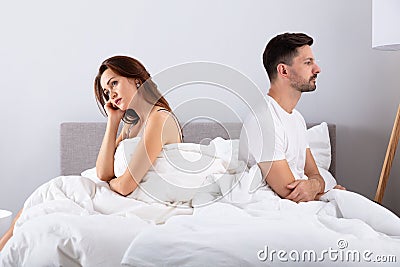 Despaired married couple sitting on bed Stock Photo