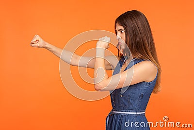 Side view of determined brunette girl with fighting spirit in casual dress punching with fists Stock Photo