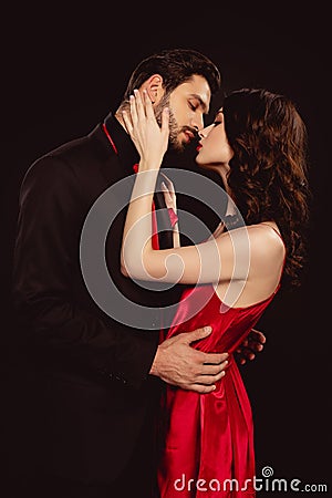 Side view of elegant woman in red dress kissing handsome boyfriend in suit Stock Photo