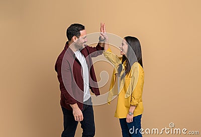 Side view of excited man and woman smiling and giving high-five to each other while celebrating success. Cheerful young couple Stock Photo