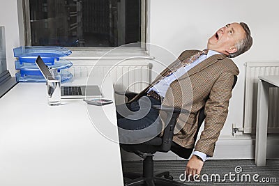 Side view of exhausted middle-aged businessman in front of laptop in office Stock Photo