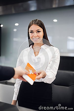 Side view of handsome man wearing glasses giving passport to staff at check in desk at airport Stock Photo