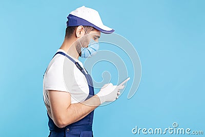 Side view, workman in overalls and gloves typing on mobile phone, using cellphone messenger to accept online order Stock Photo