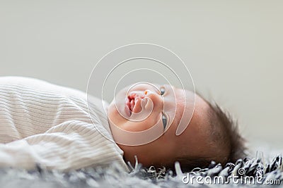 Side view happy newborn baby lying on a carpet looking at camera and smile comfortable and safety.Happiness Cute Asian newborn Stock Photo
