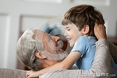 Overjoyed older mature granddad embracing little grandson. Stock Photo