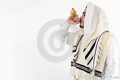 Side view of a Jewish man in tallith blowing the Shofar against a white background. Stock Photo