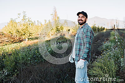 Side view latin farmer man standing in the middle of the farmland. Agricultural sustainability. Stock Photo
