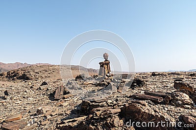 Side view of a lone stone man sitting on a rock, appearing be be just resting next to the road. These lone men are a mystery found Stock Photo