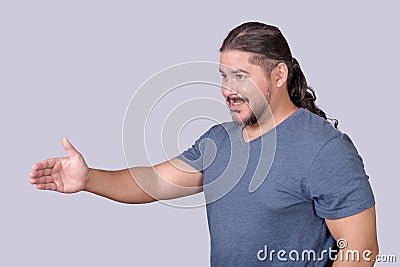 Side view of a long haired man in casual clothing extending his hand for a handshake. A friendly guy welcoming someone or offering Stock Photo
