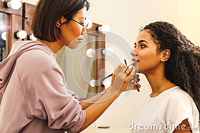 Side view of a makeup artist applying lip paint Stock Photo