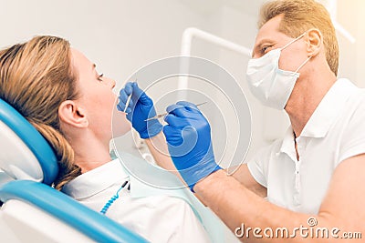 Side view on male dentist examining teeth of female patient Stock Photo