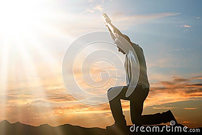 Man Kneeling And Praying At Sunset Stock Photo