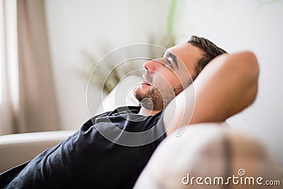 Side view Man lying and relaxing on the couch at home in the living room Stock Photo