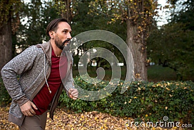 Side view of man running in autumn forest. Stock Photo