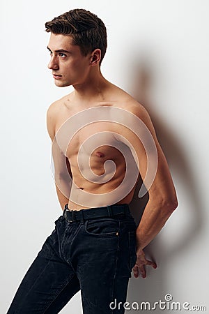 Side view of a man in trousers with a bare torso leaning against the wall Stock Photo