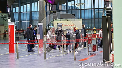 Side view of masked people stand at the check-in counters. Due to coronavirus pandemic international flights canceled Editorial Stock Photo