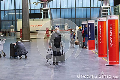Side view of masked people stand at the check-in counters. Due to coronavirus pandemic international flights canceled Editorial Stock Photo