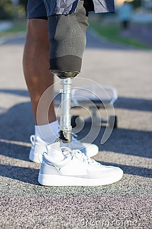 Side view of mechanical male leg in sneaker on skateboard Stock Photo