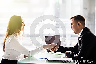 Side view of man and woman partners shaking hands over the table, maintaining eye contact, confident entrepreneurs ready for effec Stock Photo