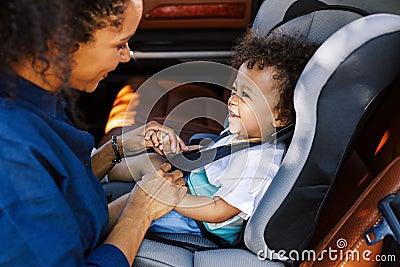 Side view of a mother helping toddler get buckled Stock Photo