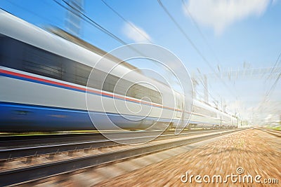 Side view of the moving ultra high speed train runs on rail way with railway infrastructure in the blurred background with flare e Stock Photo