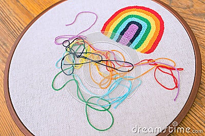 Side view of multicolored cotton fibers, mesed on a hooped grey fabric and embroidered rainbow on it Stock Photo