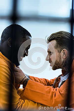 side view of multiethnic prisoners threatening each other Stock Photo