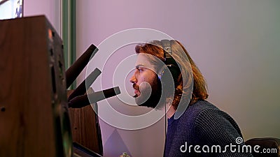 Side view of a narrator or commentator speaking his mind into a microphone. Media. Young man with headphones talking Stock Photo