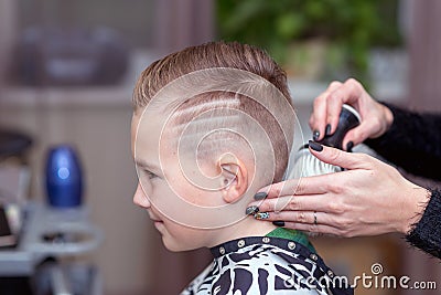 Side view Nice european boy getting hairstyle in barbershop.hairdresser makes a hairstyle for boy Stock Photo