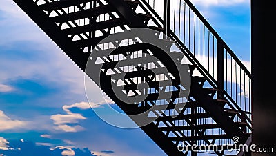 Side view of outside metal staircase or fire exit stair with sheet against blue sky. moving up concept idea Stock Photo