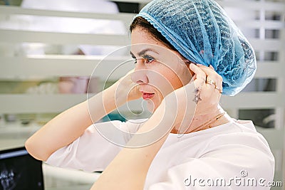 Side view photo of a stomatologist woman putting on medical uniform to begin her working in the dental clinic. Stock Photo