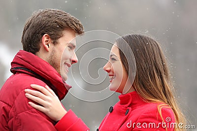 Happy couple in love looking each other in winter Stock Photo