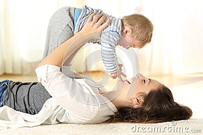 Happy mother on the floor raising her baby son Stock Photo