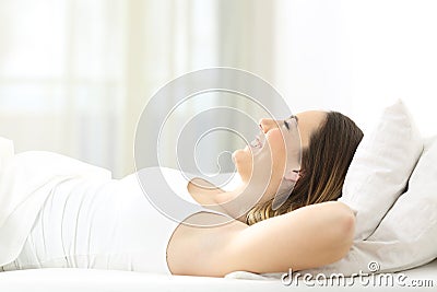 Happy woman resting lying on a bed looking up Stock Photo