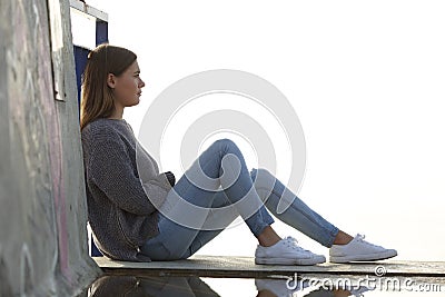 Pensive teenage girl looking away sitting outdoors Stock Photo