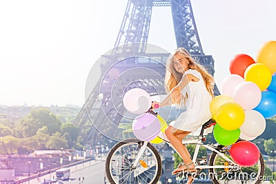 Girl cycling through Paris with balloons bouquet Stock Photo