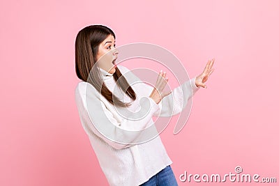 Side view portrait of scared female with raised arms, sees something awful, afraids, stop gesture. Stock Photo