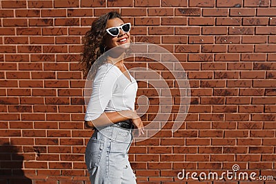 Side view portrait of young beautiful happy woman in casual cloth against brick wall Stock Photo