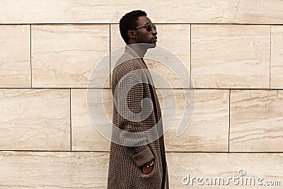 Side view profile stylish african man model wearing brown knitted cardigan, sunglasses on city street over brick wall Stock Photo